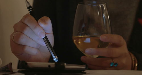 Close-up of hand holding wine glass on table