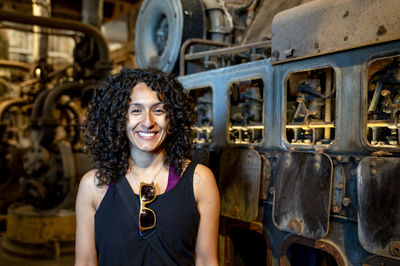 Portrait of a mixed race woman smiling while posing inside an abandoned factory.