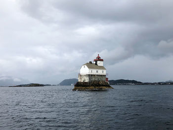 Lighthouse sailing on sea against sky