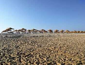 Lounge chairs on sand against clear sky