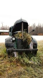 Abandoned car on field against clear sky