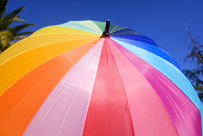 Low angle view of multi colored umbrellas against blue sky