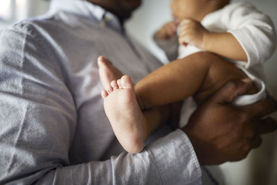 Midsection of father carrying son at home