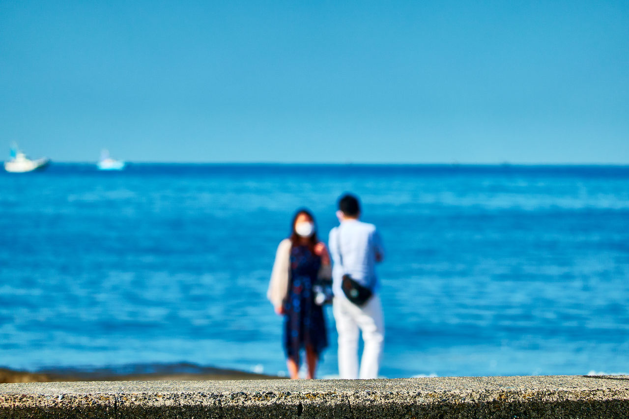 REAR VIEW OF MEN STANDING ON BEACH