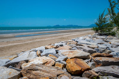 Rocks on beach against blue sky