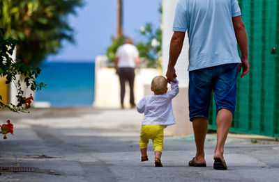 Rear view of father and son walking on floor