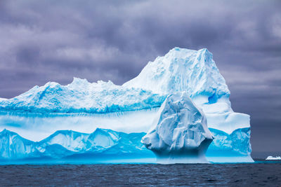 Ice floating on sea against snowcapped mountains