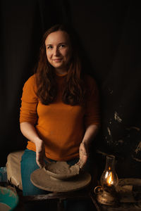 Woman makes plate of clay in pottery workshop, smiles, happy, beautiful, background, authentic 