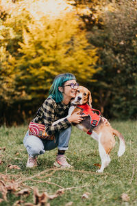 Portrait of young woman with dog on field