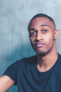 Portrait of young man with blue wall background and black shirt