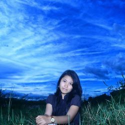 Portrait of smiling young woman on field against sky