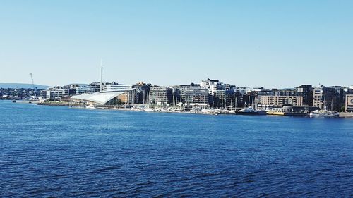 City at waterfront against blue sky