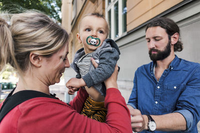 Mid adult parents with baby boy outside house