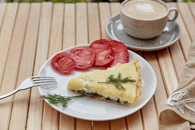 Traditional natural vegetarian cheese pie with mushrooms, tomatoes and dill. cup of coffee. 