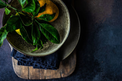 Holiday place setting with fresh organic tangerine fruits on rustic background with copy space