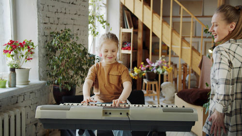 Smiling mother teaching piano to daughter