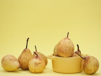 Close-up of fruits in plate against yellow background