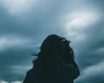 Rear view of woman against cloudy sky