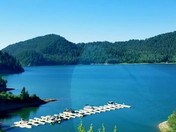 Scenic view of lake and mountains against clear blue sky