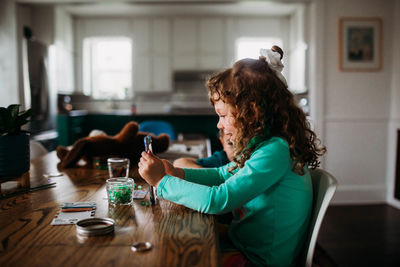 Side view of woman using phone while sitting on table