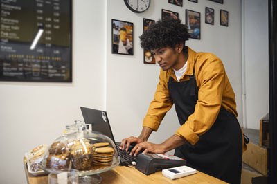 Barista working on laptop at counter in coffee shop