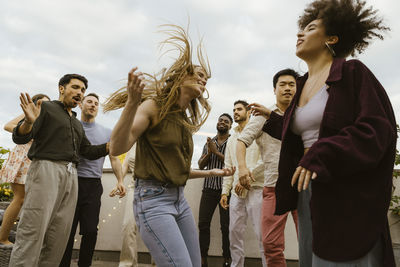 Carefree woman dancing with multiracial friends at party on rooftop deck