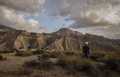 Rear view of man standing on mountain against sky