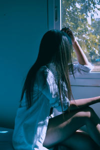 Rear view of woman sitting at home