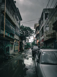 Wet street amidst buildings in city during rainy season