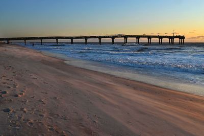 Pier over sea against sky during sunset