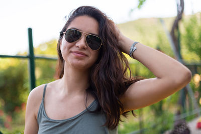 Portrait of young woman wearing sunglasses while standing outdoors