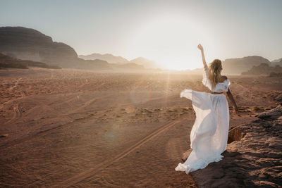 Woman in dress standing on landscape against sky