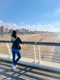 Woman standing on railing against sky