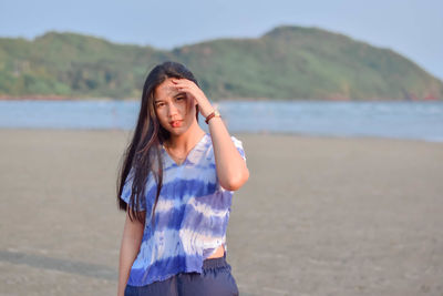 Young woman standing against sea