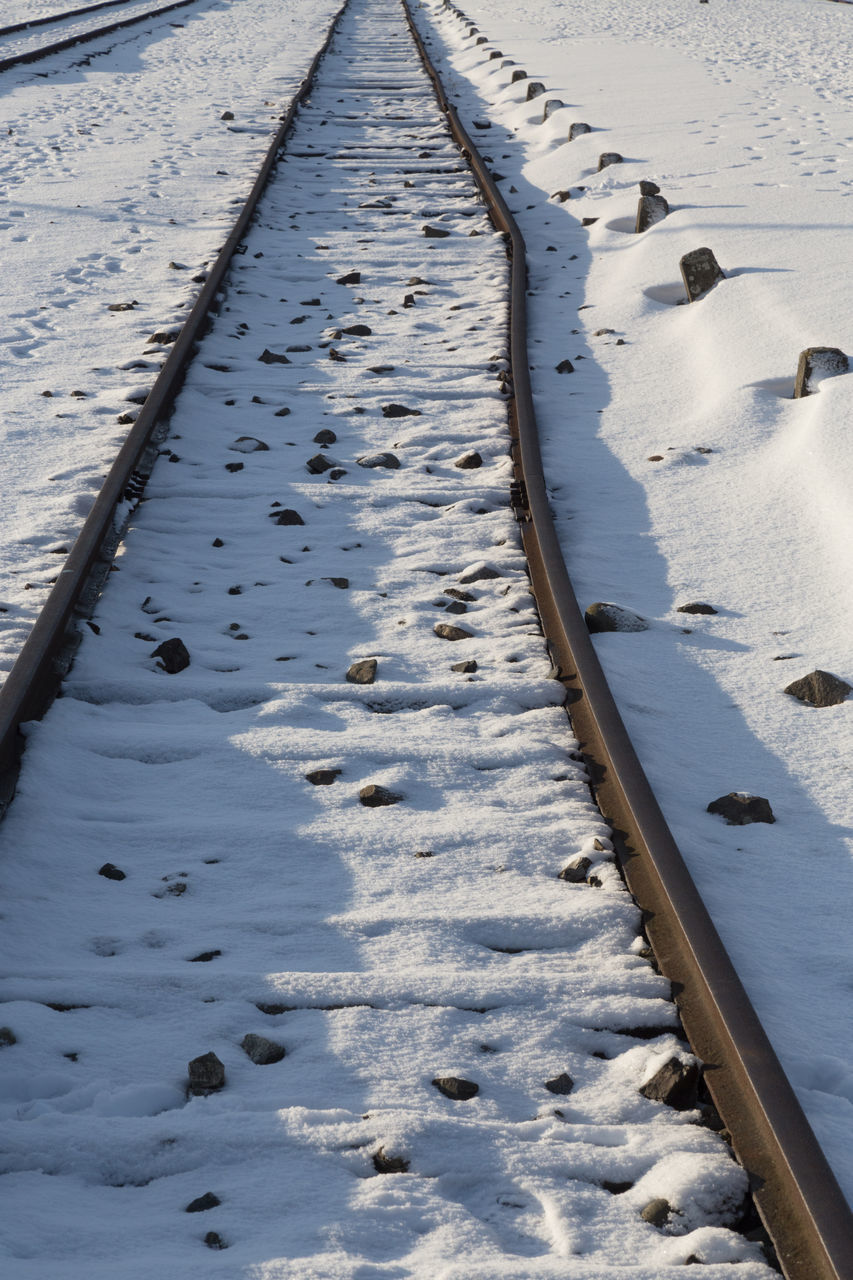 HIGH ANGLE VIEW OF SNOW COVERED RAILROAD TRACKS ON FIELD