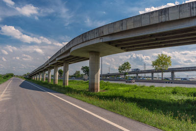 Road by bridge against sky in city