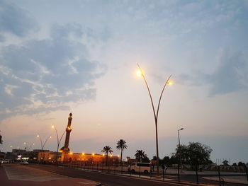 Road by trees against sky during sunset