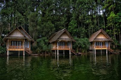 House by lake and trees against sky