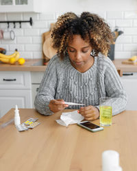 Young woman using mobile phone while sitting on table