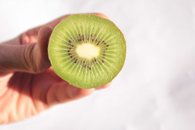 Close-up of hand holding apple against white background