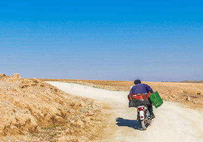 Rear view of man riding motorcycle on road