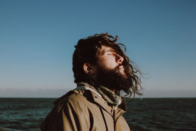 Portrait of man looking at sea against clear sky