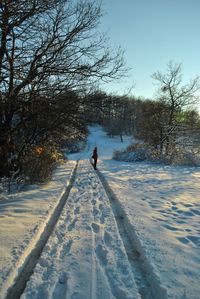 Woman standing on snow covered field against sky