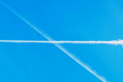 Low angle view of vapor trails in blue sky