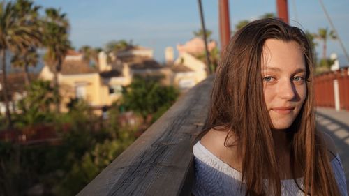 Portrait of teenage girl with long brown hair by railing