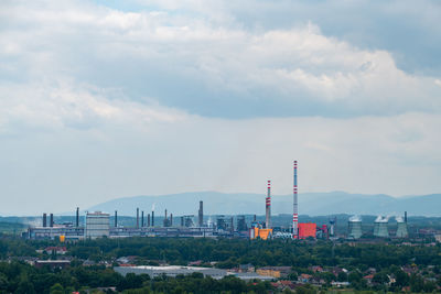 Factory by buildings against sky