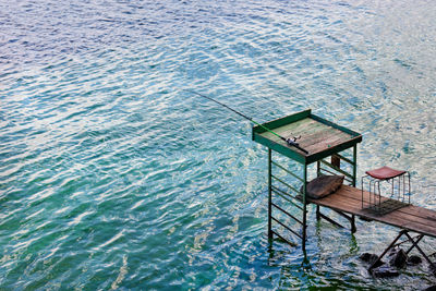 Fishing spinning rod on a high wooden platform near the river bank in the early morning.