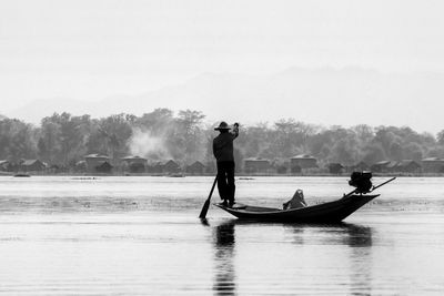 Men standing on boat in lake against sky