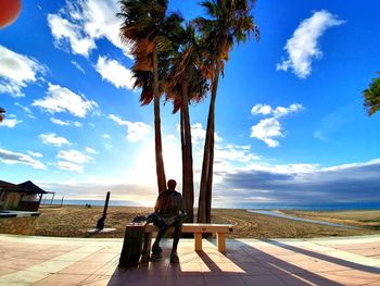 Man sitting on bench against sky