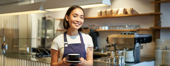 Portrait of young woman standing in cafe